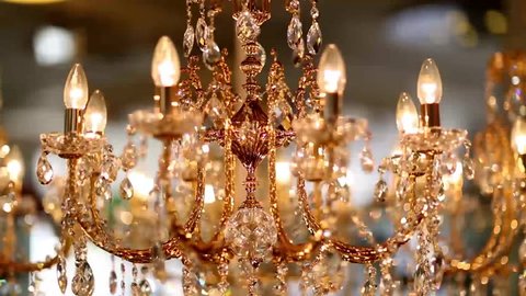 A crystal chandelier with crystals shimmers with bright lights and rotates. The ceiling light rotates and is brightly reflected in the mirror. Volumetric golden lamp with crystals rotates smoothly.