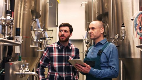 Brewers maintaining record on digital tablet at brewery