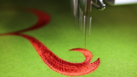 fast Sewing machine while embroidering with red thread on green background