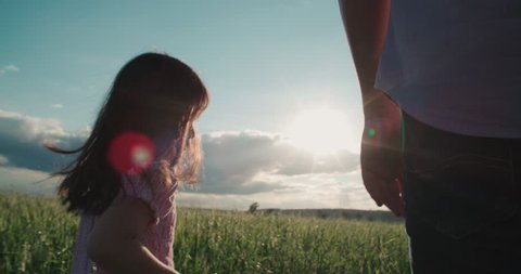 little Asian girl running on the green field and holds the hand of his father, slow motion