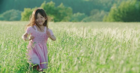 little Asian girl running on the green field and holds the hand of his father, slow motion Video stock