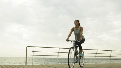 Beautiful young sexy lady riding her bycicle near the sea.