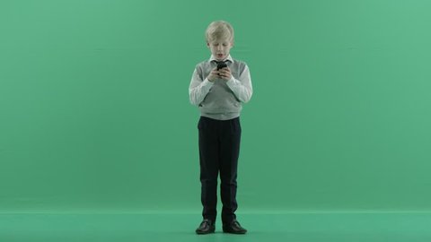 schoolboy is using the cell phone on green screen background