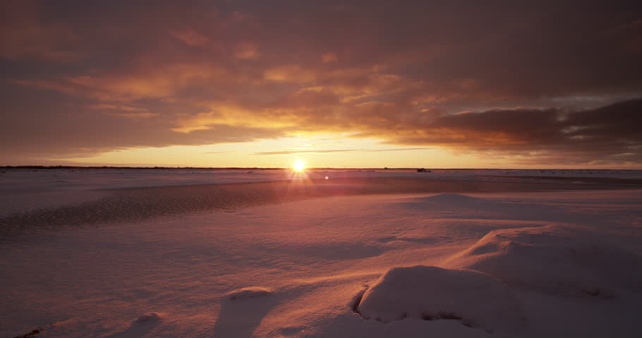 Time lapse - clouds rushing over tundra at sunset with snow