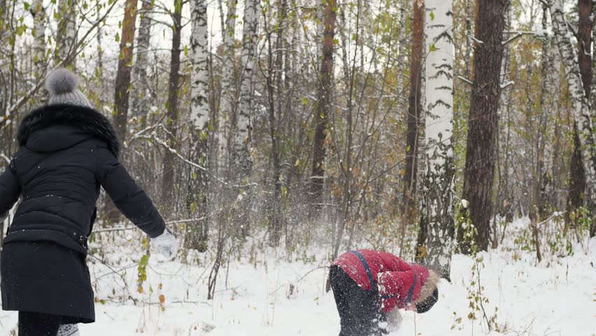 family playing by throwing snowballs in the winter Park