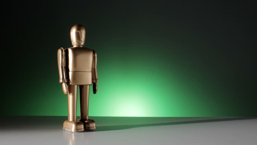A gold colored robot walks from left to right toward the camera