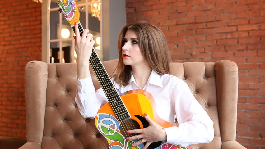 Girl in white shirt posing with a guitar in hippie style