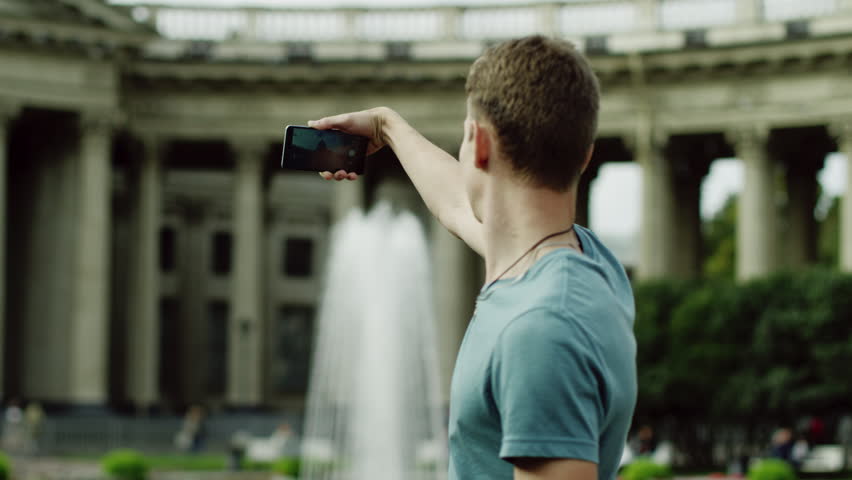 The back and side view of a man doing selfie.