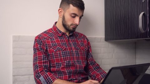 Attractive Young Man Work on Laptop in Kitchen