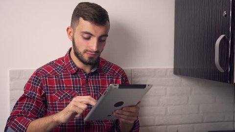 Attractive Young Man Use Tablet in Kitchen