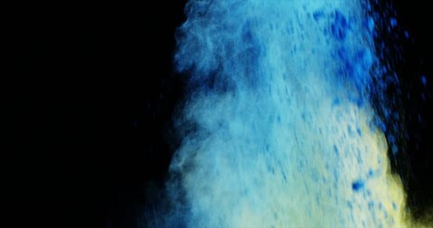 Close-up of blue and yellow dust powder blowing against black background 4k