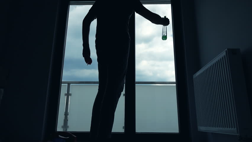Silhouette of young man with detergent cleaning window at home
