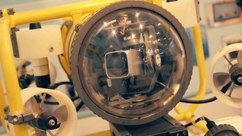 Autonomous underwater robot explorer of yellow color with a video camera behind a thick and durable glass and lamps 