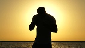 Silhouette of a muscular african american young man athlete standing and practicing 