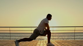 Healthy african american young sportsman doing stretching exercises on pier
