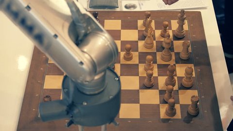 Robot playing chess with a man. Hand manipulator moves the chess and presses the key of the control watch