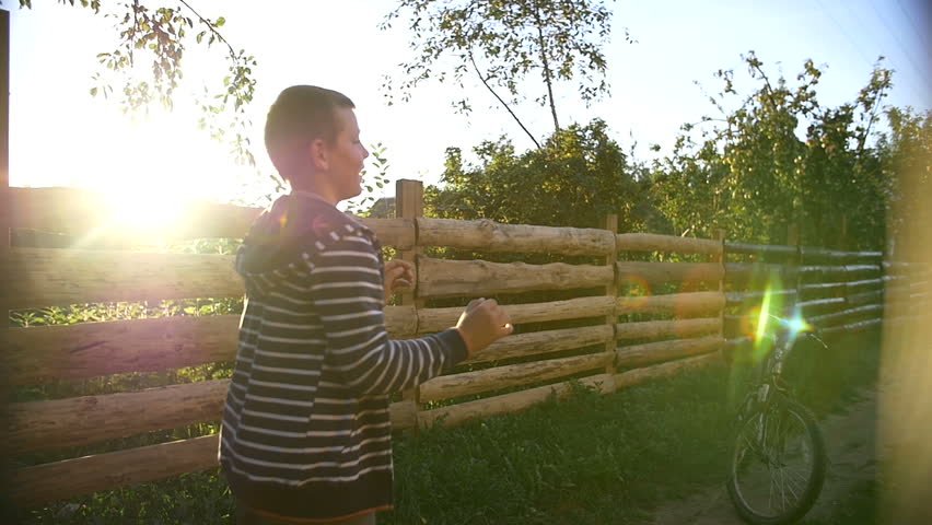 Two boys playing ball outdoors at sunset in the country