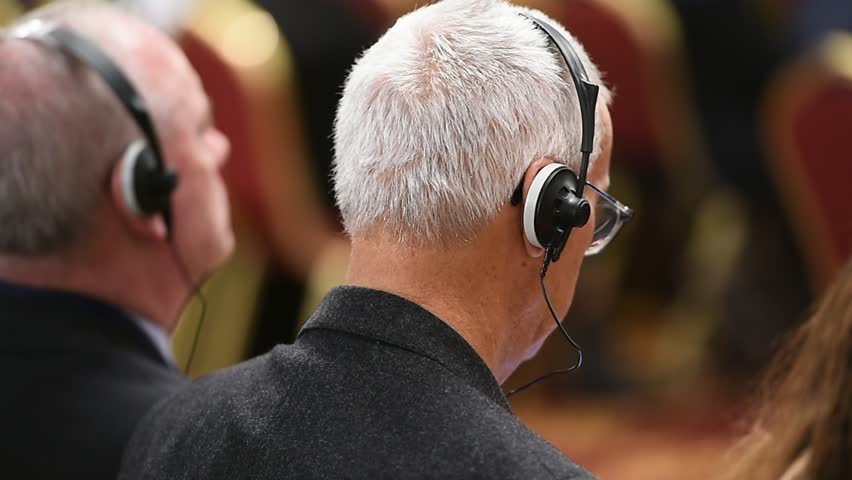 Unrecognizable person using in ear headphones for translation during event