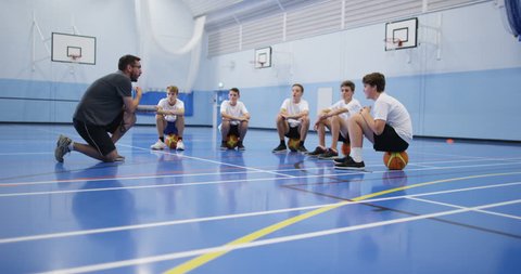 4k, A male coach talking to a group of teenage boys during a physical education class.