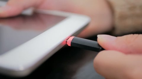 Woman's hand plugging black charging cable into pc digital tablet - USB data cable connecting on modern gadget. Close up shot