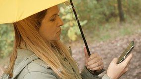 Female on mobile phone while holding yellow umbrella outdoor 4K 2160p 30fps UltraHD footage - Surfing on wireless internet woman in nature  3840X2160 UHD video