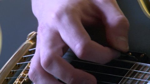 Super closeup shot of hand playing the guitar strings with mediator