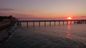quadrocopters flying over the sea and a wooden pier, sunset