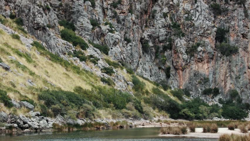 Landscape view, cliffs, bushes, stones and flowing river.
