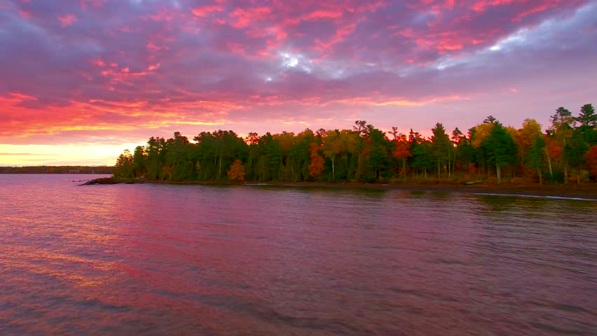 Dramatic red dawn over Fall colors in Copper Harbor Michigan, moving aerial view.
