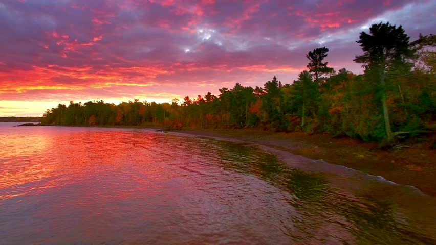 Dramatic red dawn over Fall colors in Copper Harbor Michigan, moving aerial view.
