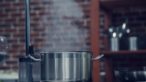 Saucepan with steam. The steam comes from the pan on the stove. The steam from cooking. Aromas of cooking. Boiling water. Boil. Metal pan. Cooking. Cooking. Household. Cooking of soup. First course