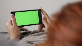Redhead woman relaxing with chroma key greenscreen tablet slow motion 1080p FullHD footage - Female  holding green screen smart phone while in bed slow-mo  1920X1080 HD video