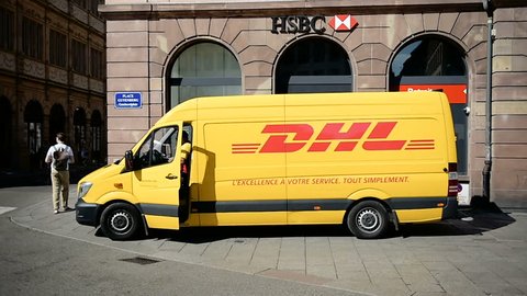 STRASBOURG, CIRCA 2016: DHL delivery van leaving after distributing parcels with HSBC bank branch behind in the center of the city


