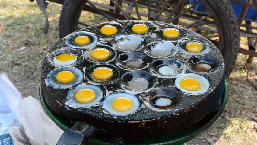 frying bird eggs in hole pan of thailand market