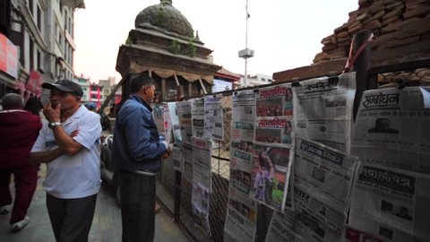 KATHMANDU, NEPAL - APRIL 8, 2016: Newspapers on fence that hides the damage because of earthquake on 25 April, 2015. Durbar square. Evening