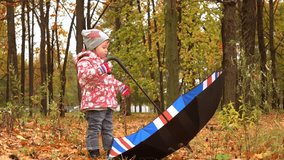 Little girl playing with big umbrella in autumn park. Bad weather concept. 4K steadicam video