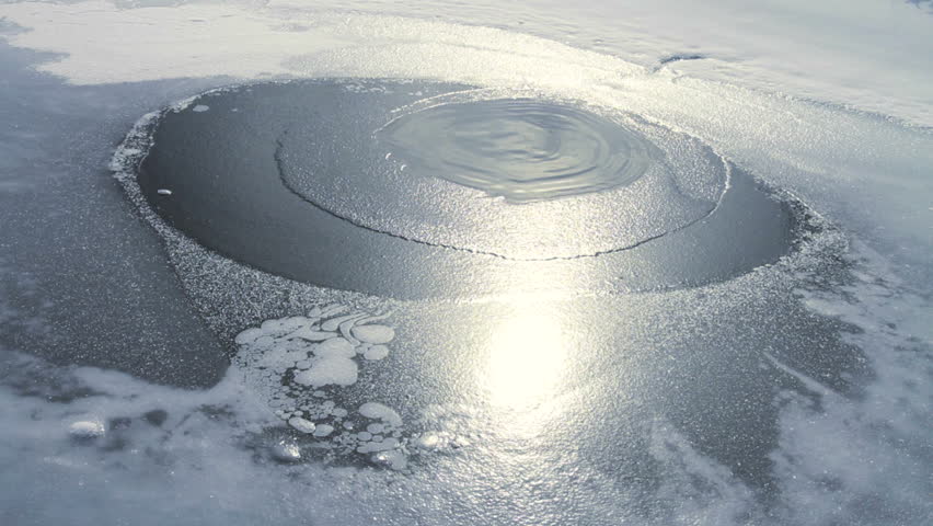 Open water spring of a frozen winter lake  with sun reflection