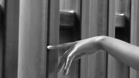 Closeup hand of woman gently grazes metal modern wall - black and white video in slow motion