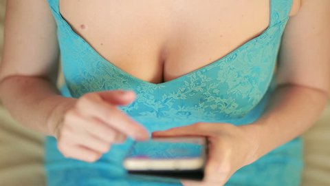 girl with big boobs uses cellphone. sexy woman holding a smart phone