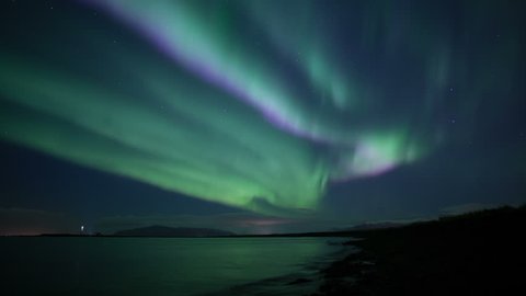 Bright green purple aurora borealis ocean beach Grotta lighthouse Reykjavik Iceland 4k
