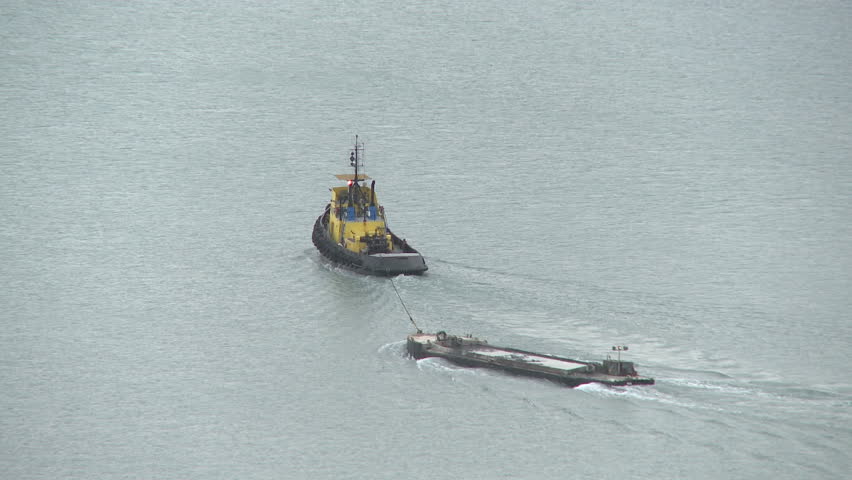 Tugboat pulls a barge of silt out to sea