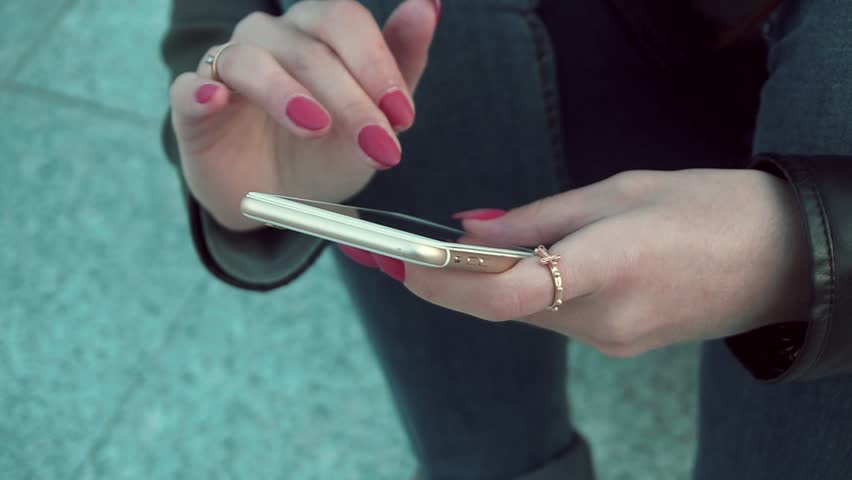 Woman using app on smartphone smiling and texting on mobile phone. Beautiful multicultural young casual female professional on mobile phone. Mixed race Caucasian Caucasian model.
