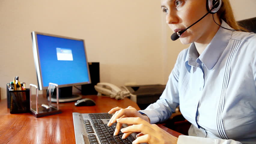 Businesswoman in headphones speaking and sitting on the workdesk 