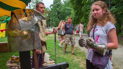 EVENTS IN LJUBLJANA JULIJ-AVGUST 2016 A young girl is having iron gloves on her hands and she is alsolooking at the iron helmet that a young man is showing her. Close-up shot.