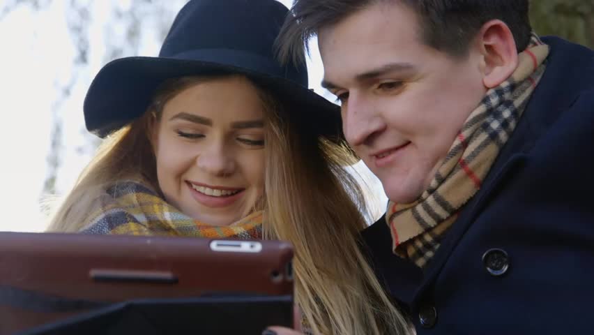 Happy couple sitting together and using tablet