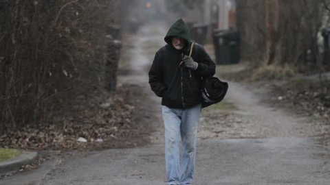 Homeless man walking in an alley
