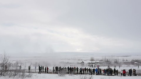 Slowmotion of Geyser Strokkur eruption in Iceland in winter on a cloudy day surrounded by tourists