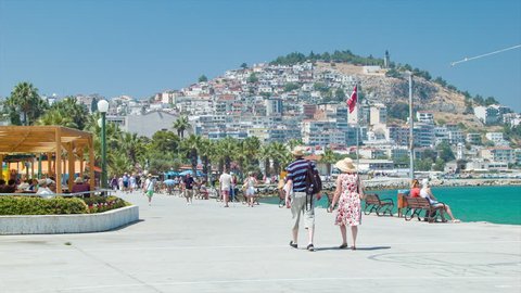 KUSADASI, TURKEY - 2016: Visiting Foreigners on Seafront Parade Walking Along the Vibrant Middle Eastern Aegean Oceanfront Scene during the Summer Vacation Season