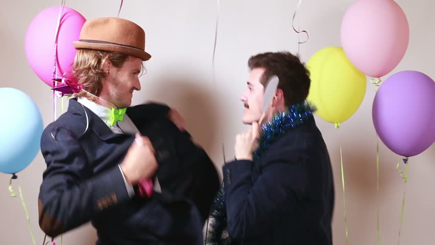 Two funny friends having fun dancing with props in party photo booth