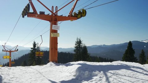 Chair lift transportation system which skiers transport while suspended off ground. Down line side of the lift that the haul rope goes down the hill. Aerial ski lift with yellow painted wooden seats